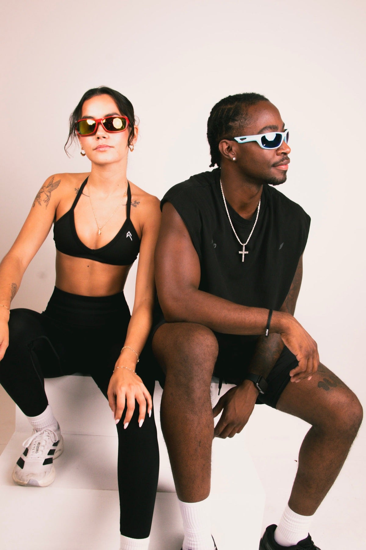 Two models seated in Edge Movement wraps, one in a red mirror lens and one in a white frame